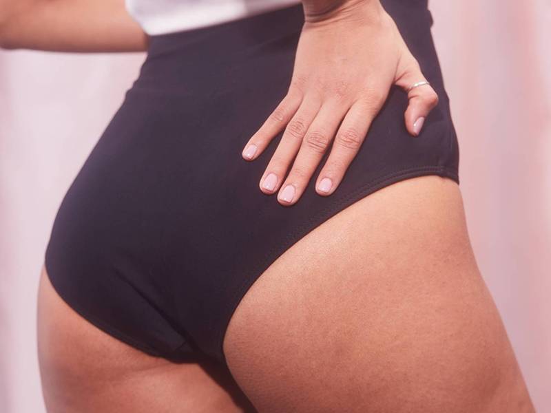 Person's butt in black underwear on pink background