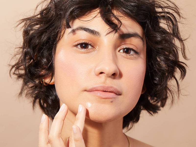 person applying spot treatment to their chin