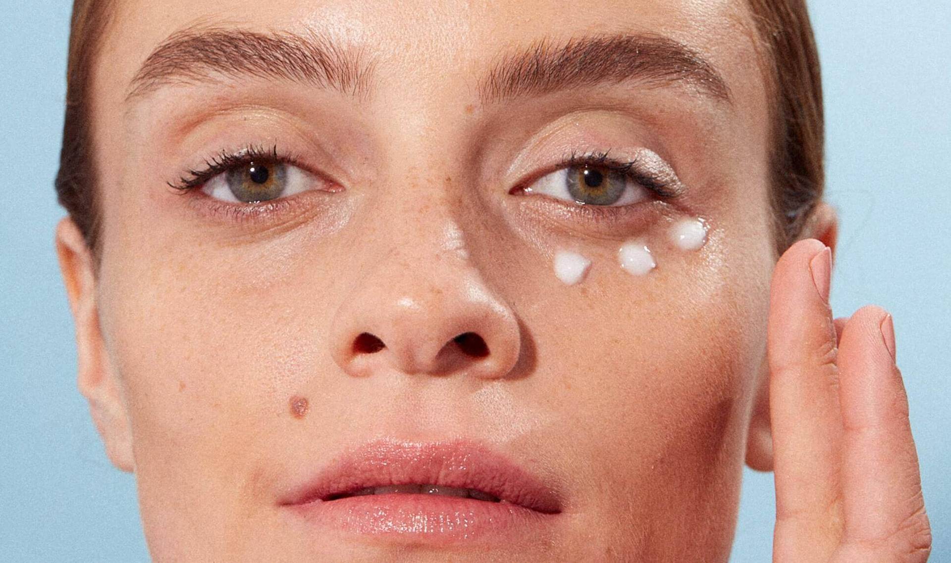 person applying moisturizer under eye