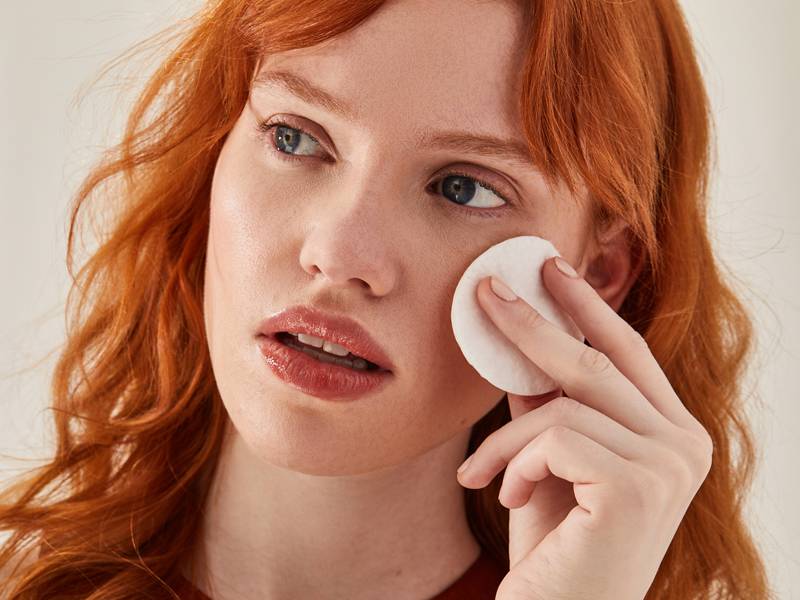 Person touching cheek with cotton round