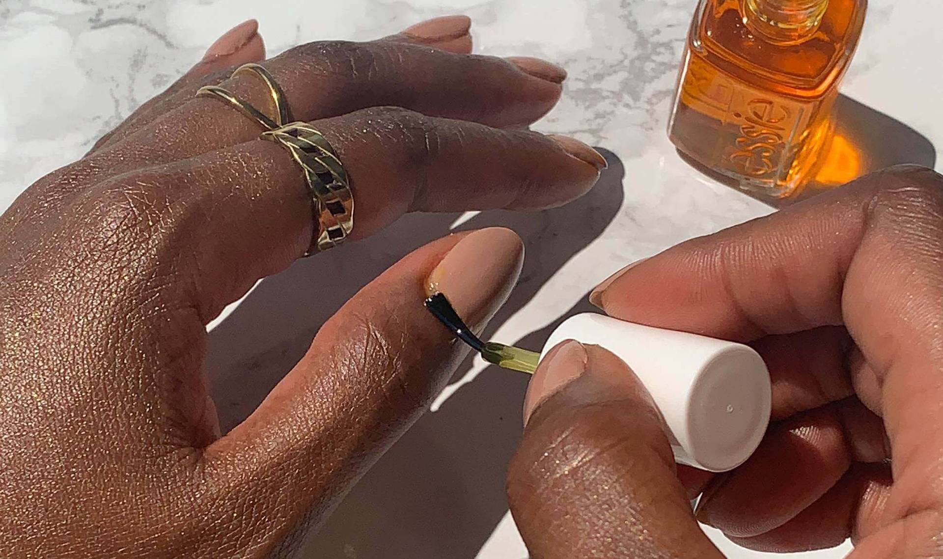 person applying cuticle oil to nail